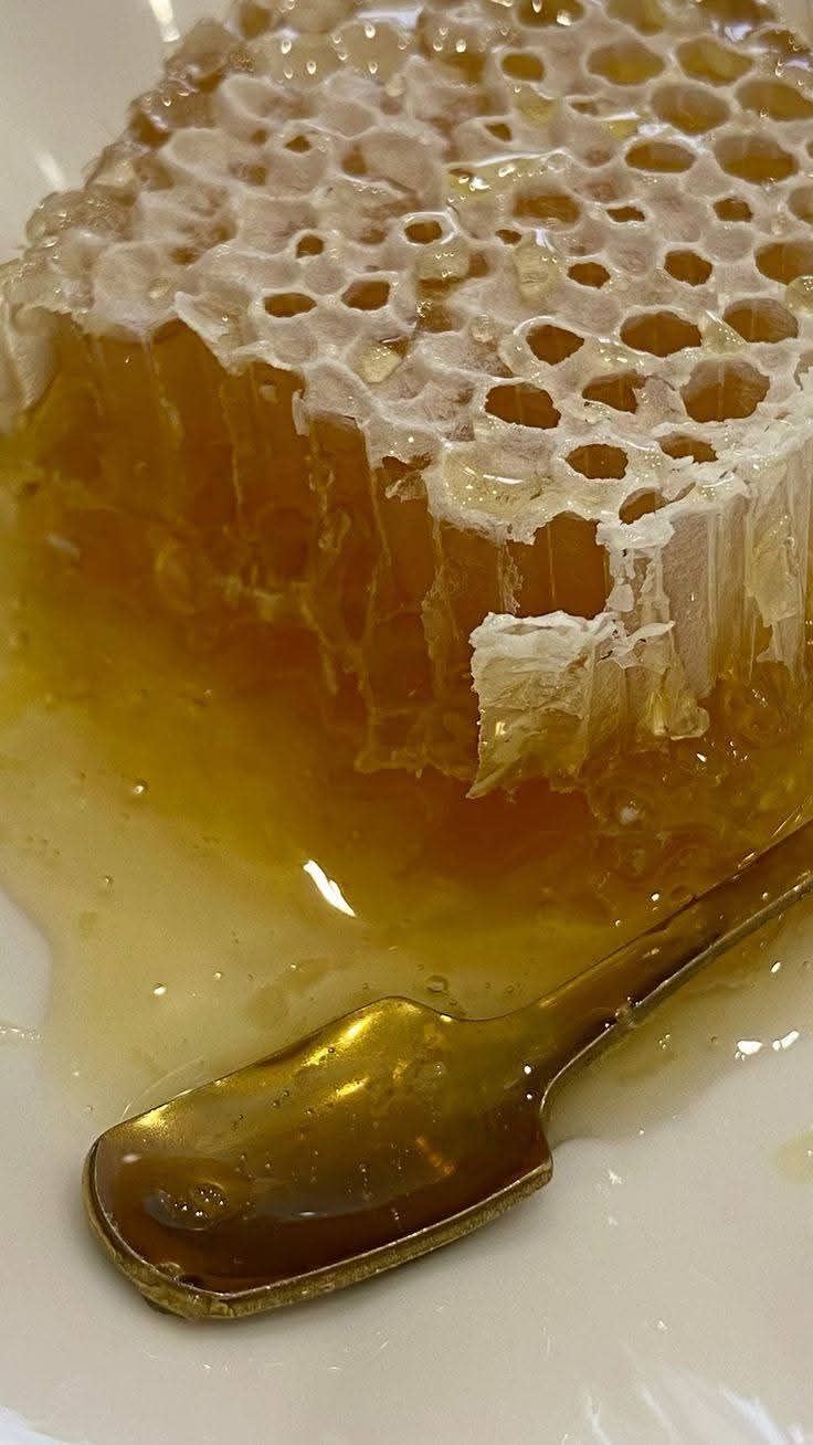 Macro close-up of golden comb honey cells with a spoon