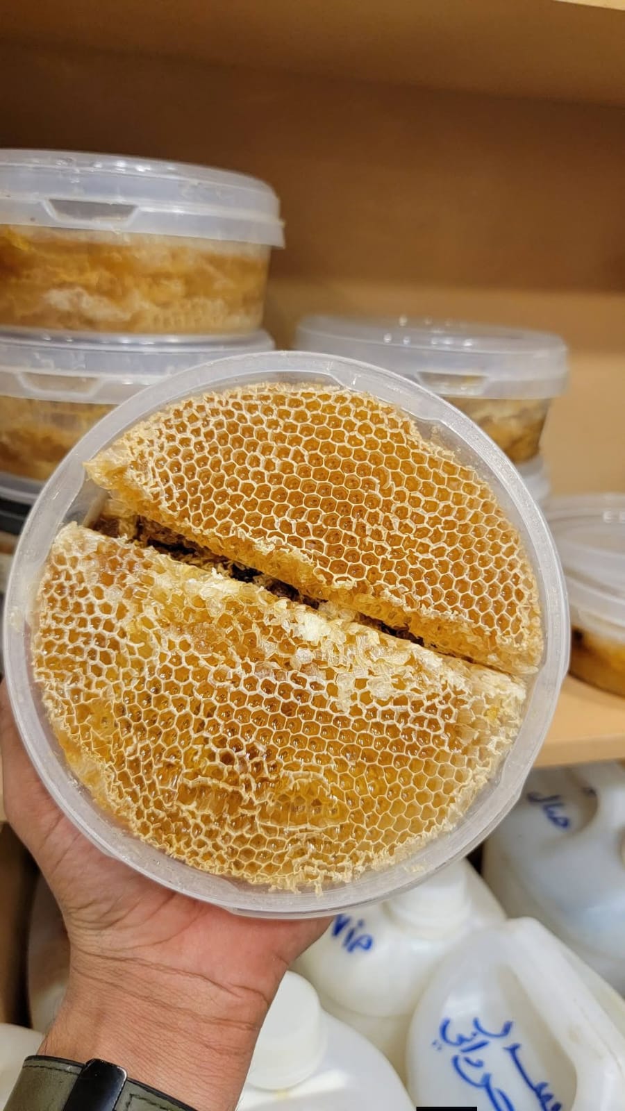 Round comb honey lifted from a tub by hand